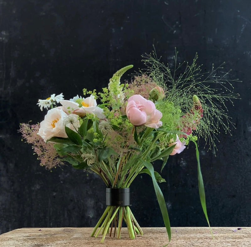 Ein zarter Strauß aus rosafarbenen Rosen, weißen Blüten und zartem Grün, der mit einem Hanataba Bouquet Twister-Spiralstielhalter ordentlich befestigt ist.