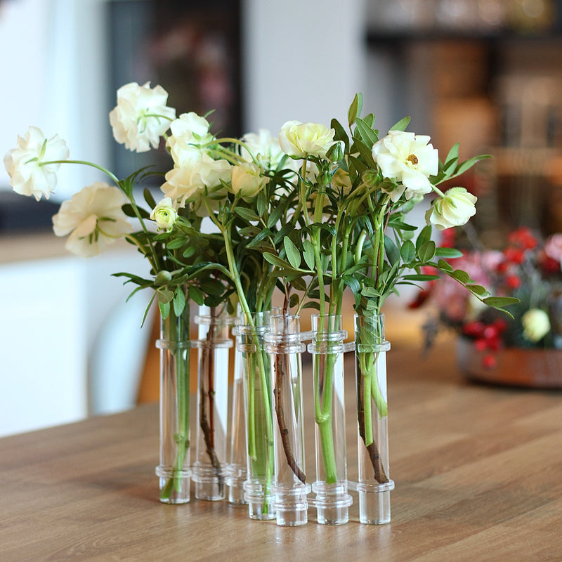 Elegante Flowerflute-Vase von Hanataba mit einem Arrangement aus frischen weißen Rosen auf einer hölzernen Tischplatte.