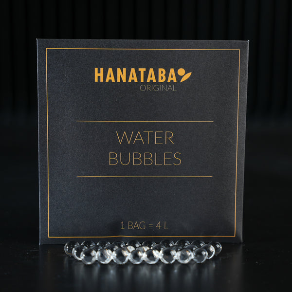 Eine raffinierte Verpackung mit der Aufschrift 'HANATABA Original Water Bubbles' und dem Text '1 BAG = 4L', begleitet von transparenten Wasserblasen auf der Vorderseite, die zur Verschönerung von Blumenarrangements dienen.