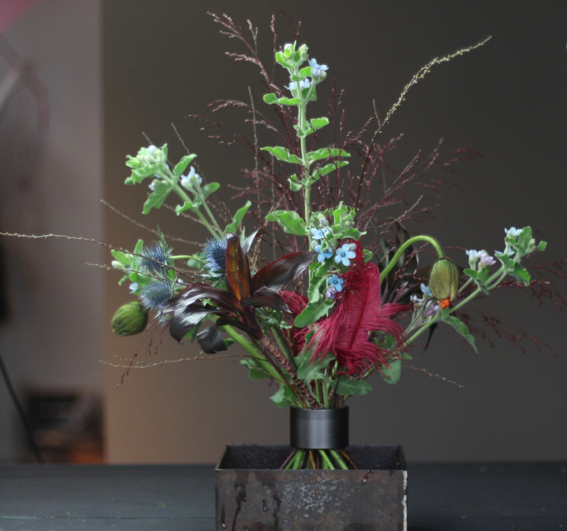 Ikebana-Arrangement mit einer Vielzahl von Blumen und Blättern, die mit einem Hanataba-Spiralstielhalter in Pechschwarz befestigt sind.